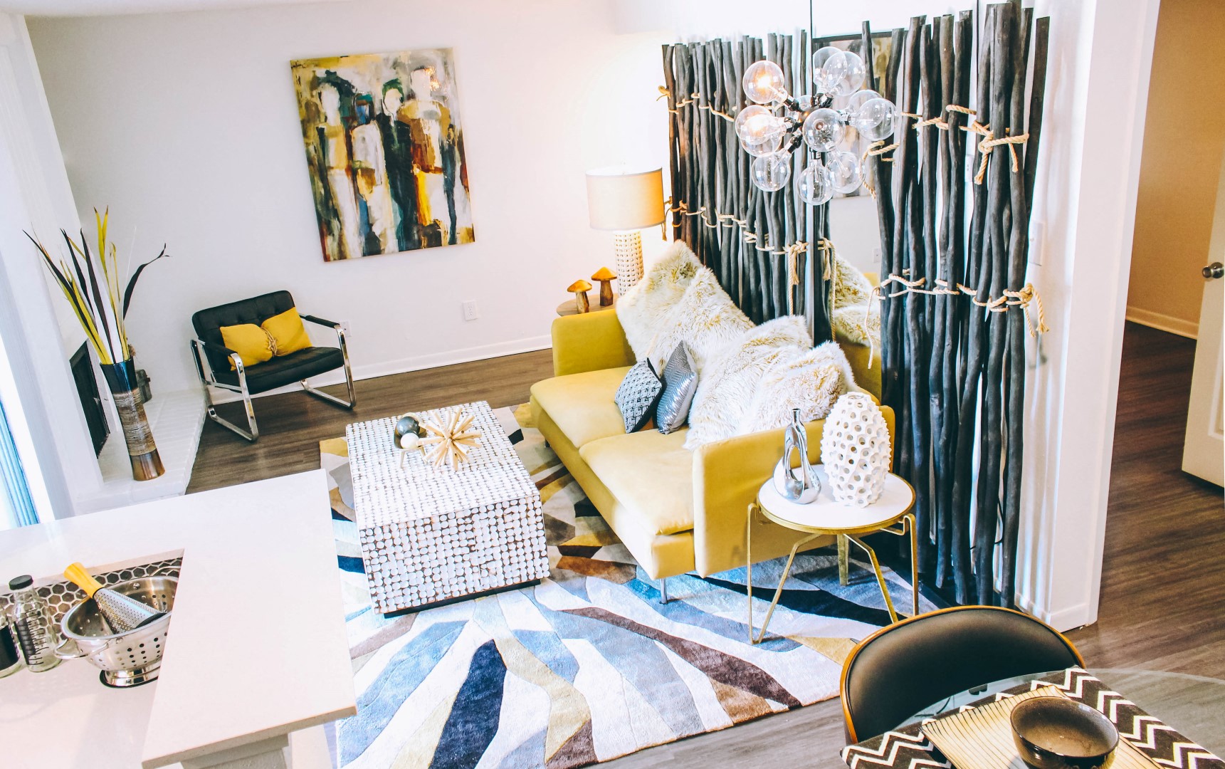 a living room with a yellow couch and a blue and white rug